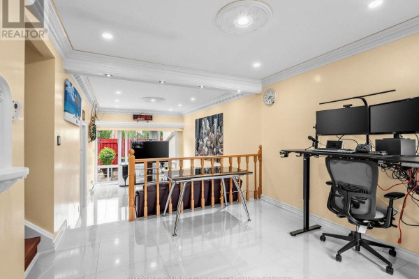 Living area with white tiled floors, beige walls, a sectional couch, and a double-monitor desk. - 86 - 2901 Jane Street, Toronto