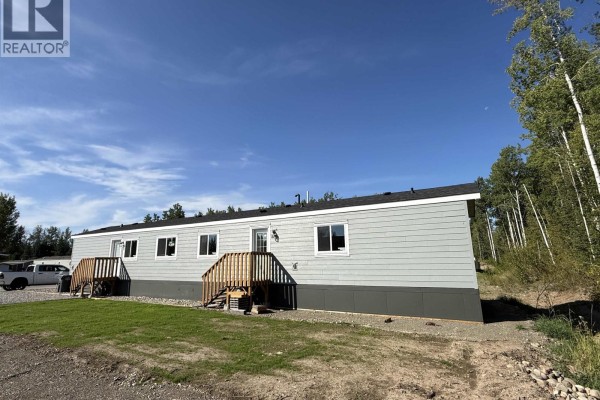 Right side exterior view of the light grey mobile home showing the entrance and the wooded area behind. - 86 313 Westland Road, Quesnel