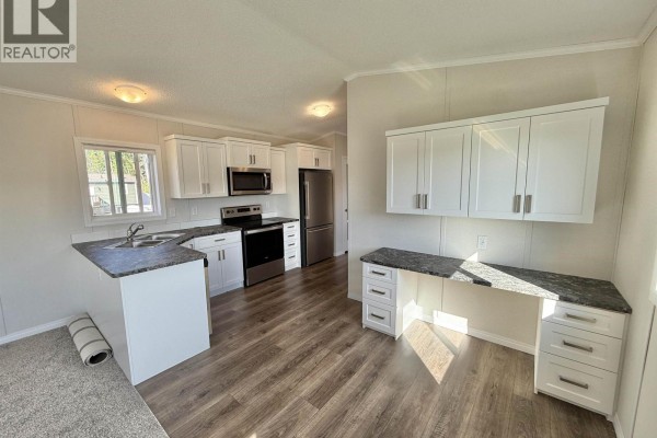Interior kitchen and workspace with white cabinets, stainless steel appliances, and granite countertops. - 86 313 Westland Road, Quesnel