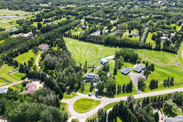 Aerial view of a rural property with multiple homes, a large field, and surrounding trees. - #86 52514 Rge Road 223, Rural Strathcona County