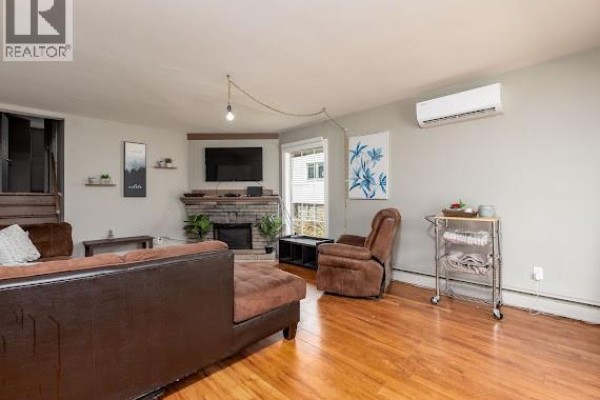 Living room with a sectional sofa, fireplace, television, recliner chair, and a rolling cart with towels. - 86-88 Somerset, Moncton