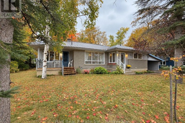 Front view of the grey brick house with a covered porch and steps, surrounded by trees. - 86 Albert Street, Selwyn