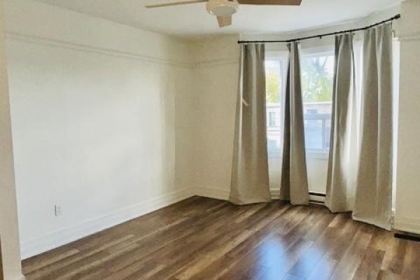 Living room with white walls, laminate flooring, and floor-to-ceiling beige curtains. - 86 Carlaw Avenue, Toronto