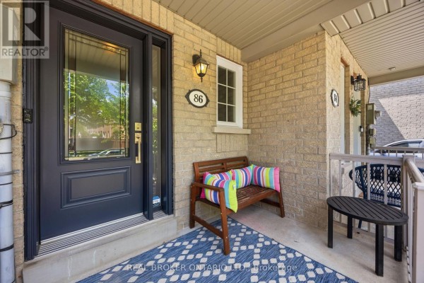 Front porch of a townhouse with a navy blue door, a wooden bench, and a patterned rug. - 86 Coleridge Drive, Newmarket