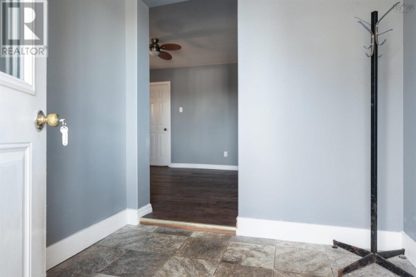Entryway looking into a hallway with grey walls, dark wood flooring, and a ceiling fan. - 86 Denoon Street, Pictou
