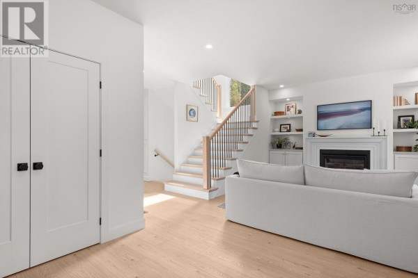 Bright living room featuring a fireplace, built-in shelves, and a view of the staircase. - 86 Double Lane, Oakfield