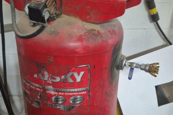 A red Husky brand industrial air compressor with brass fittings and blue valve handles. - Unit 9 - 86 Melford Drive, Toronto