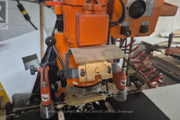 Close-up of an orange Blum woodworking machine with various levers and controls. - Unit 9 - 86 Melford Drive, Toronto
