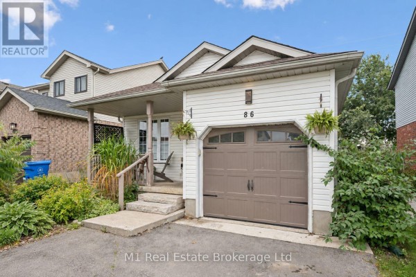 Front view of a white vinyl-sided house with a covered porch, garage, and driveway. - 86 Milligan Street, Centre Wellington