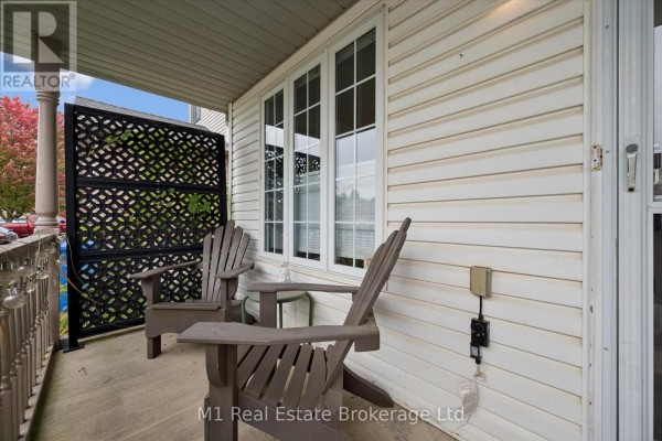 Two wooden Adirondack chairs on a covered porch with a decorative screen and white siding. - 86 Milligan Street, Centre Wellington