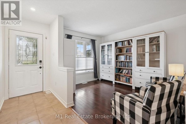 Entrance hallway with tiled floor, white door with frosted glass, and a living area with bookshelves and chairs. - 86 Milligan Street, Centre Wellington