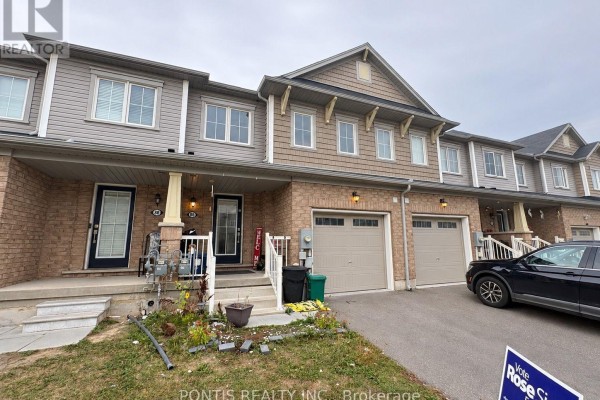 Front exterior of a townhouse unit with brick facade and beige garage door. - 86 Munro Circle, Brantford