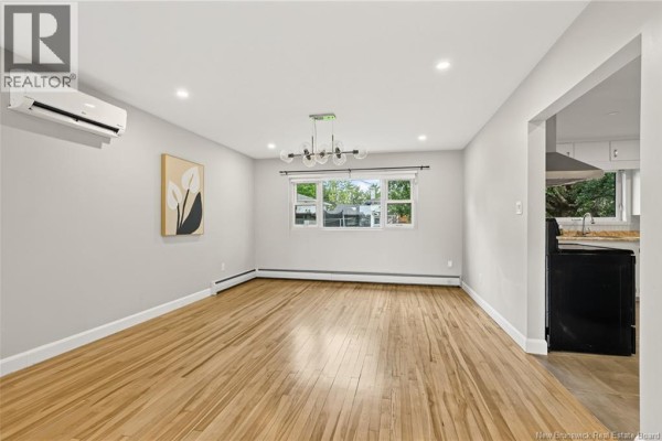 Living and dining area with hardwood floors, light grey walls, and a chandelier. - 86 Poirier Drive, Moncton