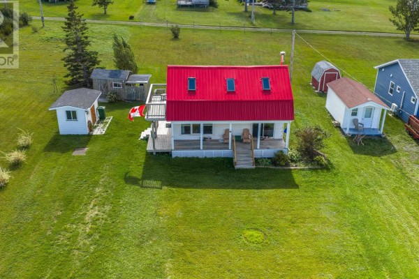 Aerial view of a white house with a red metal roof and three dormer windows. - 86 Red Cliff Drive, Seafoam