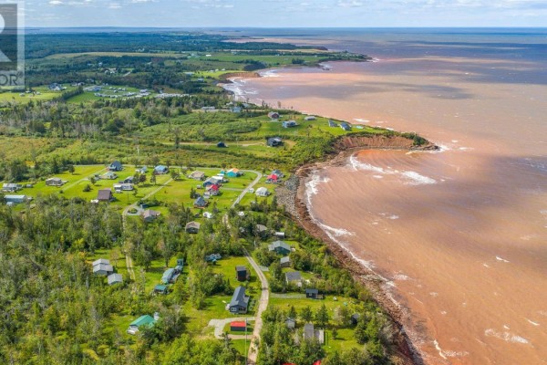 Aerial view of a coastal community with scattered houses and a red-brown ocean. - 86 Red Cliff Drive, Seafoam