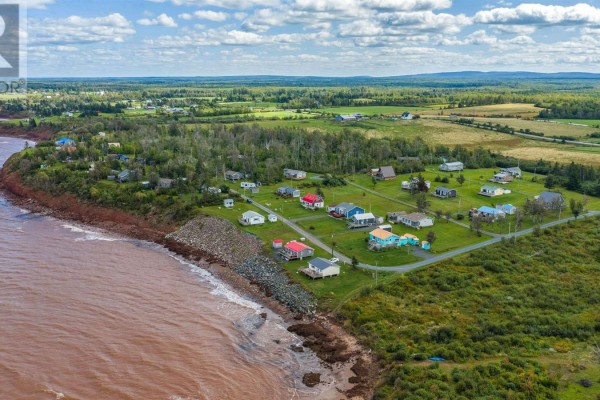 Aerial view of a seaside community with colorful houses, green lawns, and the ocean. - 86 Red Cliff Drive, Seafoam
