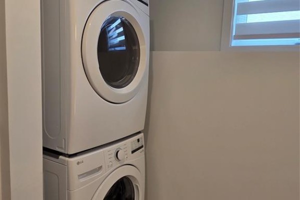 White stacked front-load washing machine and dryer in a laundry nook. - 86 Rutile Street, Clarence Rockland