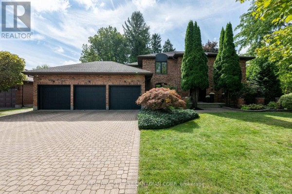 Exterior of a large brick house with a paved driveway and three-car garage doors. - 86 Tobin Court, London South