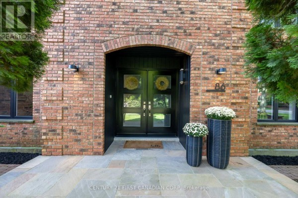Close-up of a brick house entrance with double glass doors and potted plants. - 86 Tobin Court, London South
