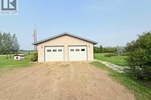 A beige detached garage with two white overhead doors and a concrete driveway. - 861023 Rr 214, Rural Northern Lights, County Of