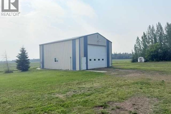 A large, light blue and white metal workshop with a large overhead door and a small side door. - 861023 Rr 214, Rural Northern Lights, County Of