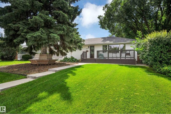 Front exterior of a white house with a dark wood deck and a green lawn. - 8615 66 Av Nw, Edmonton