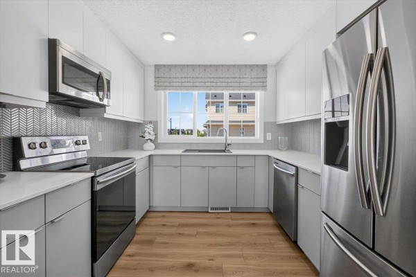 U-shaped kitchen with white countertops and grey lower cabinets. - 862 Daniels Wy Sw, Edmonton
