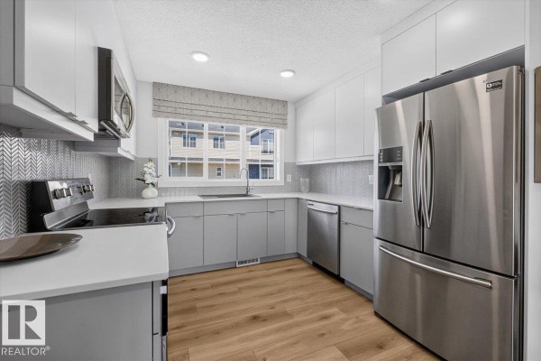 U-shaped kitchen with stainless steel appliances and a large window. - 862 Daniels Wy Sw, Edmonton