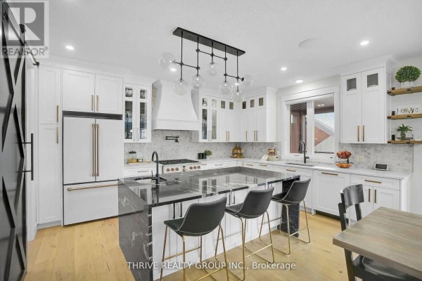 Spacious white kitchen with a large island, marble countertops, stainless steel appliances, and pendant lighting. - 862 Lunar Drive, London North