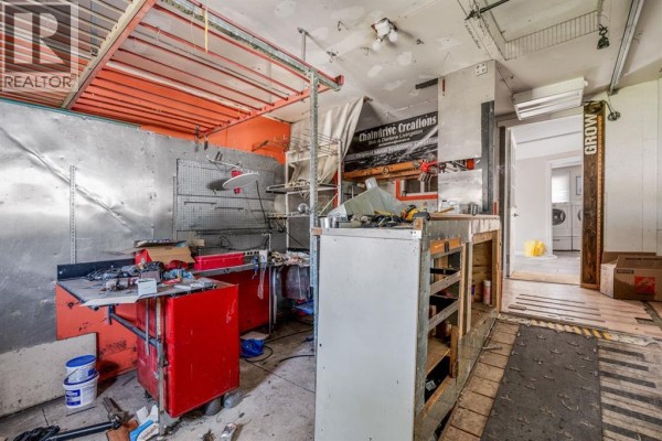 Interior view of a cluttered workshop with metal walls, tool benches, and storage shelves. - 863 2 Street E, Cardston