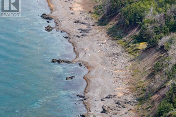 Close-up aerial view of a rocky shoreline and the ocean next to a tree-covered cliff. - 8646 Highway 337 Georgeville   B2g 2l1, Morar