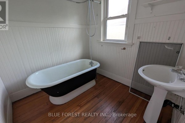 Clawfoot tub and pedestal sink in bathroom with beadboard walls - 867 Queens Avenue London East