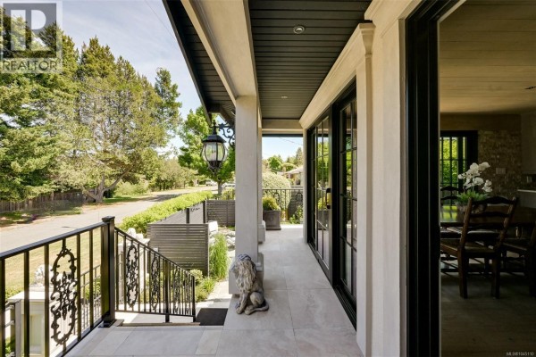 View from the covered porch looking down the steps to the street, with large glass doors and a lion statue on the porch. - 867 Victoria Ave, Oak Bay