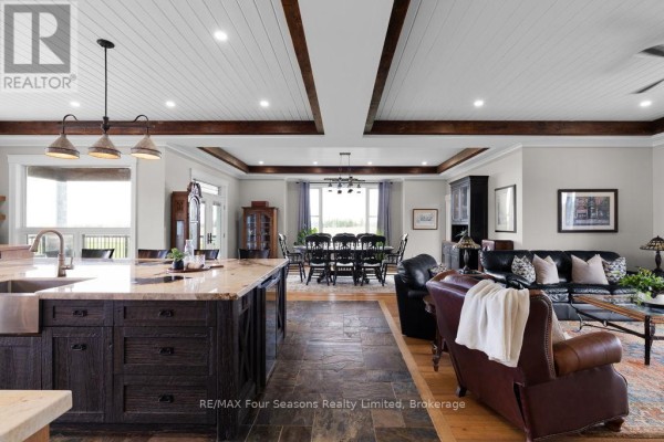 Living room with kitchen island, dining set, leather sofas, and wood beam ceiling.