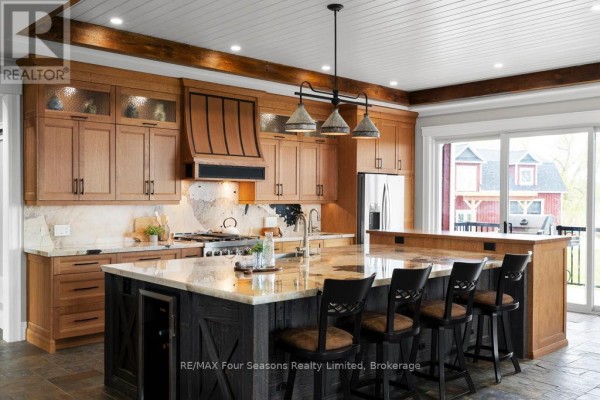 Modern kitchen with island, bar stools, stainless steel appliances, and large windows - 8672 County Rd 91 Road Clearview