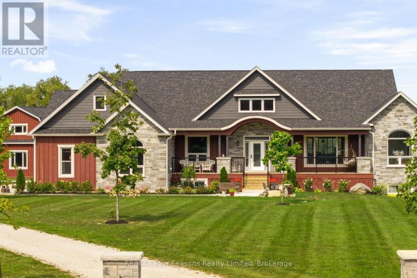 View of the red house across a reflective pond, set in a grassy field with trees in the background. - 8672 County Rd 91 Road, Clearview