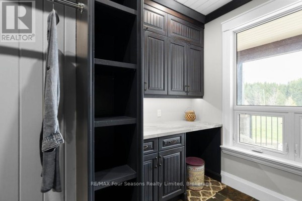 Laundry room with dark cabinets, open shelves, and a large window - 8672 County Rd 91 Road Clearview