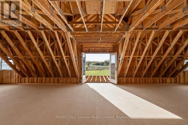 Unfinished attic with exposed beams and French doors opening to a field view - 8672 County Rd 91 Road Clearview