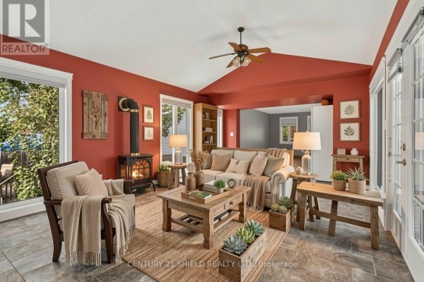 Living room with red walls, a wood-burning stove, large windows, and rustic wood furniture. - 868 Laflin Street, Cornwall