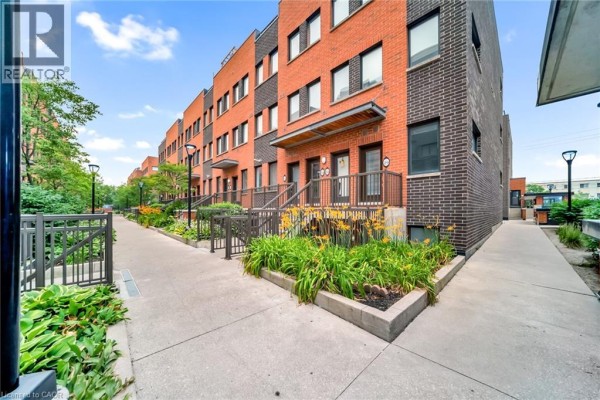 Pathway between red brick townhouses with stairs, railings, and green bushes. - 869 Wilson Avenue Unit# 29, Toronto