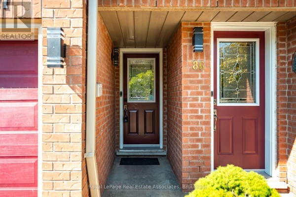 Close-up of a townhouse entrance with brick facade and dark red front doors. - 87 - 6950 Tenth Line W, Mississauga