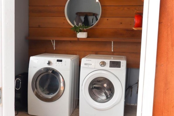 Stackable white Samsung washer and dryer with wooden accent wall and shelf. - 87 5250 Beaver Harbour Rd, Port Hardy