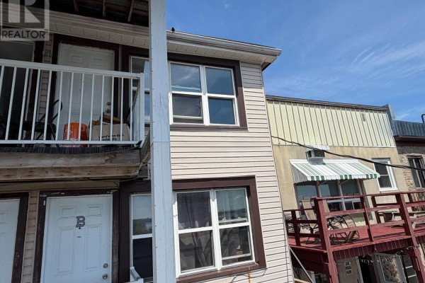 Exterior view of two separate apartment entrances with white doors and balcony railing. - 87-93 King Street W, Brockville