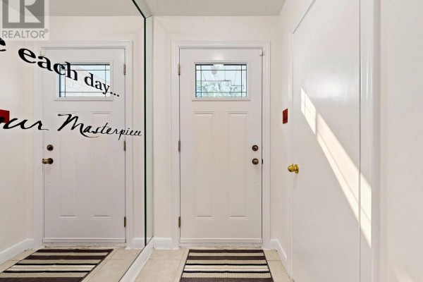Interior hallway with two white doors, a mirrored wall, and striped entryway mats. - 87 Combe Avenue, Toronto