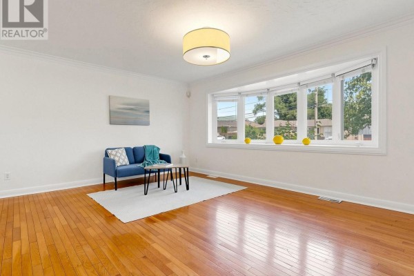 Living room featuring a bay window, hardwood floors, a blue sofa, and a white rug. - 87 Combe Avenue, Toronto