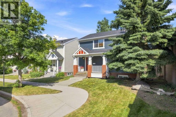 Side view of the blue two-story house with a sidewalk curving through the front lawn. - 87 Couture Crescent Sw, Calgary