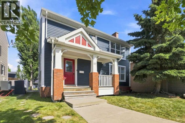 Close-up of the blue house exterior, focusing on the porch and red front door. - 87 Couture Crescent Sw, Calgary