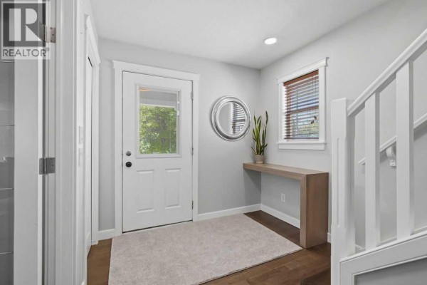 Interior entryway with a white door, round mirror, and a narrow console table. - 87 Couture Crescent Sw, Calgary