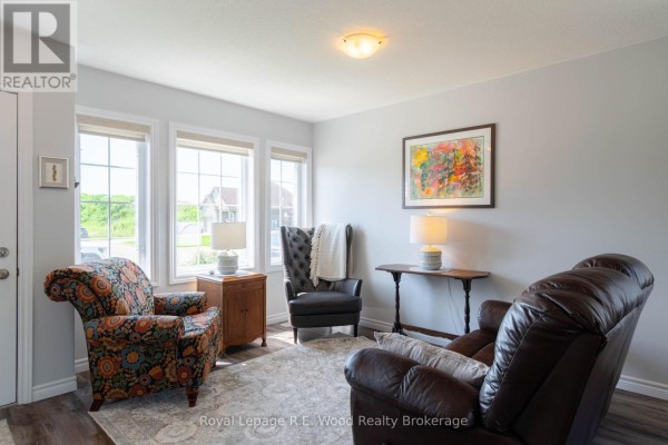 Living room seating area with patterned armchair, dark leather chair, leather recliner, and end tables. - 87 Irving Drive, Norwich