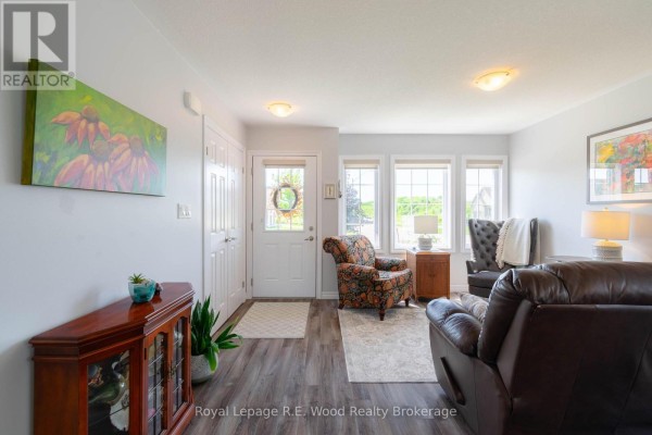 Living room and kitchen area with brown leather sofa, dining table, white cabinets, and stainless steel appliances. - 87 Irving Drive, Norwich